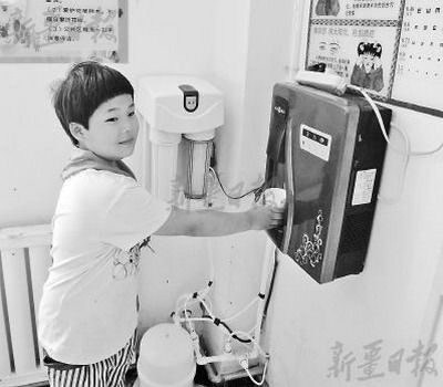 库车县第12小学的学生陈芯蕊在新装的饮水机上接水